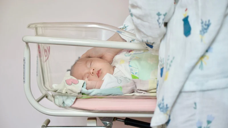 Śpiący noworodek w pustym, bezpiecznym łóżeczku