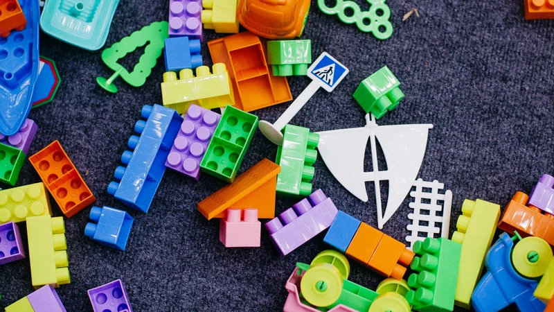 Sterta jaskrawych plastikowych klocków na ciemnym dywanie